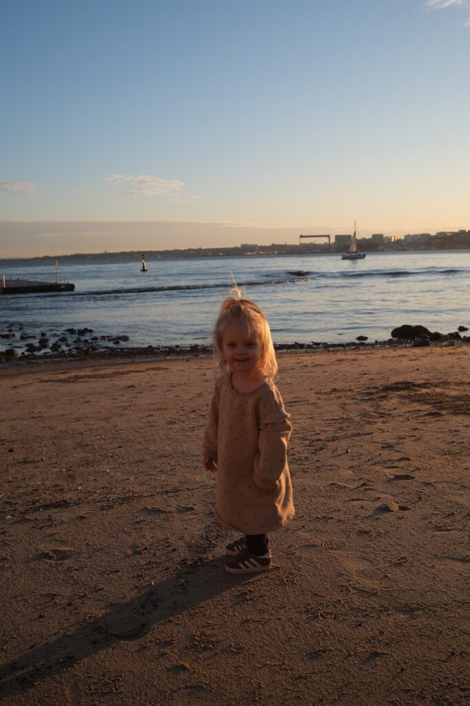 A young girl on the beach at sunset.